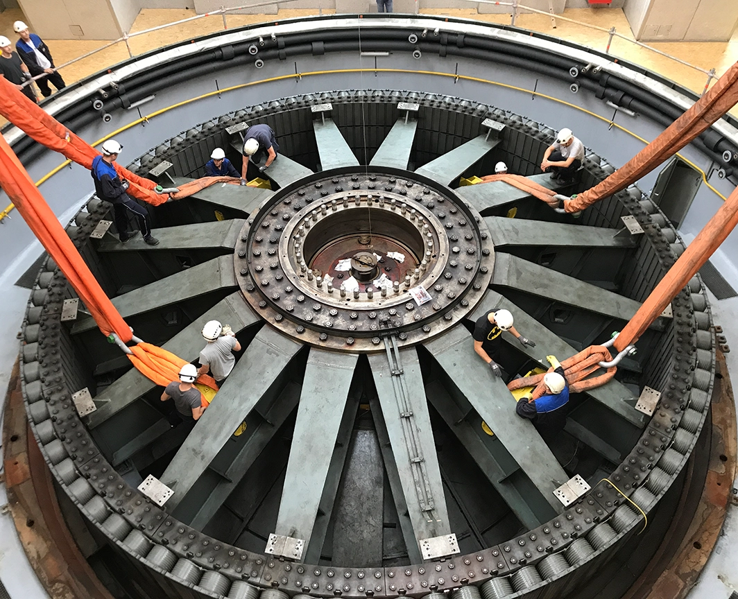 Das Bild zeigt wie die neue Turbine im Kraftwerk eingebaut wird. Sie hat mittlerweile ihren Bestimmungsort gefunden.  Wir blicken von oben auf die neue Installation.