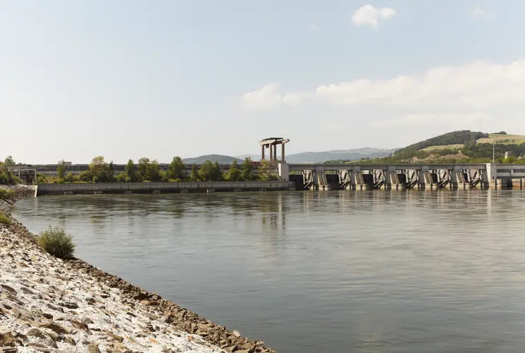 Im Mittelgrund sehen wir das Kraftwerk Melk im Frühling. Die Donau ist ruhig und der Himmel blau.