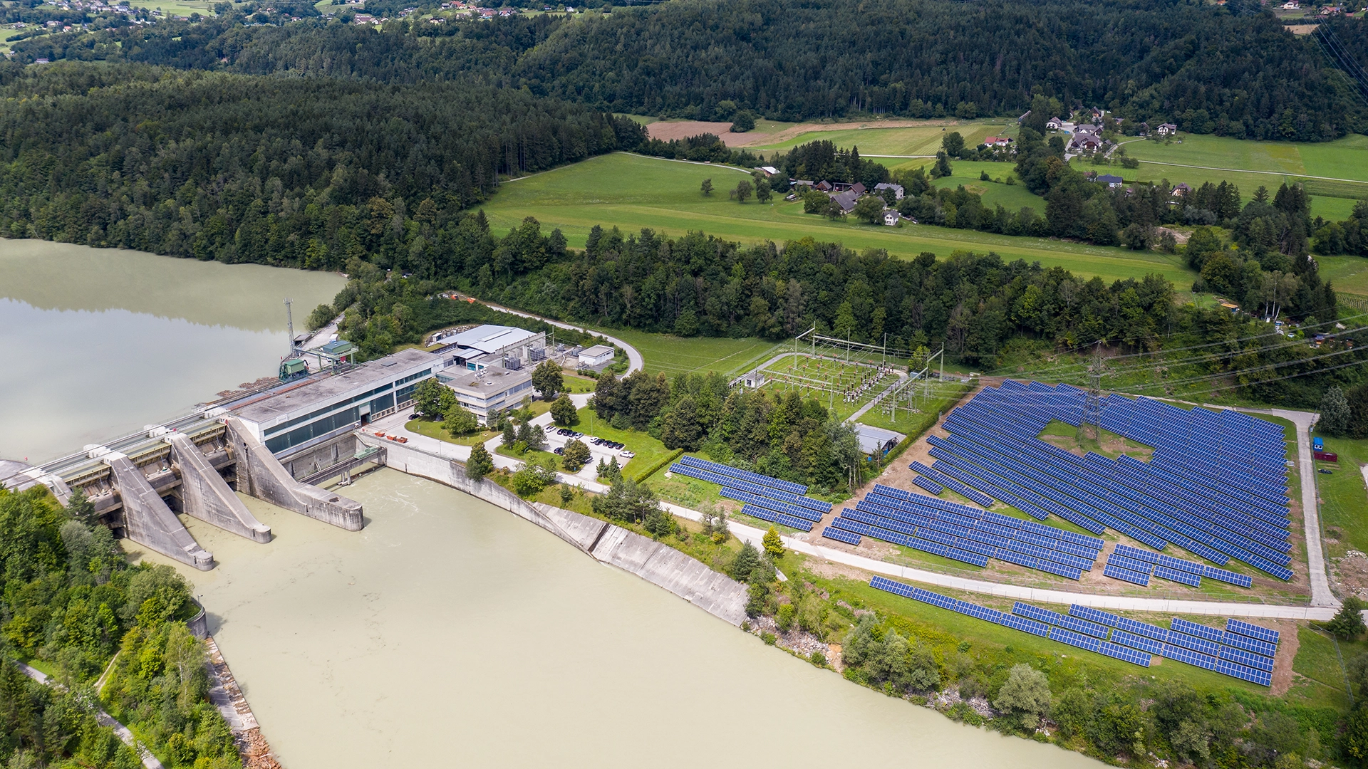 Das Wasserkraftwerk Feistritz an der Drau zeigt sich aus der Vogelperspektive. Auf der rechten Seite sieht man außerdem eine große PV-Anlage.